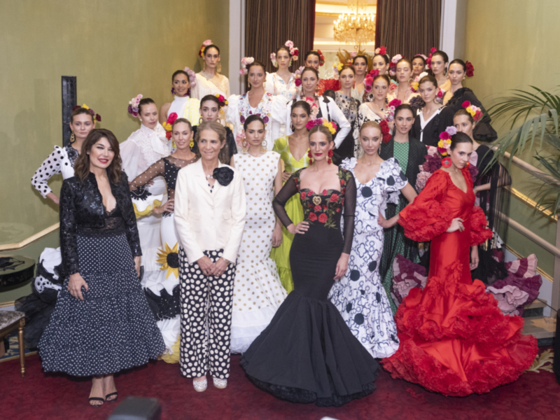 Desfile de moda flamenca con modelos en trajes tradicionales y elegantes en un salón decorado con lujo.
