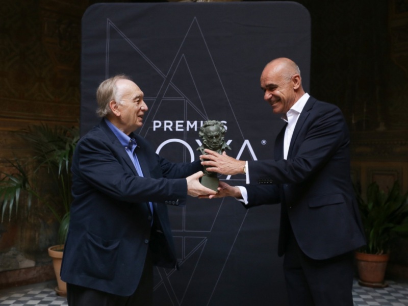 Entrega del Premio OXIA: un hombre recibe un busto de otra persona en una ceremonia formal.