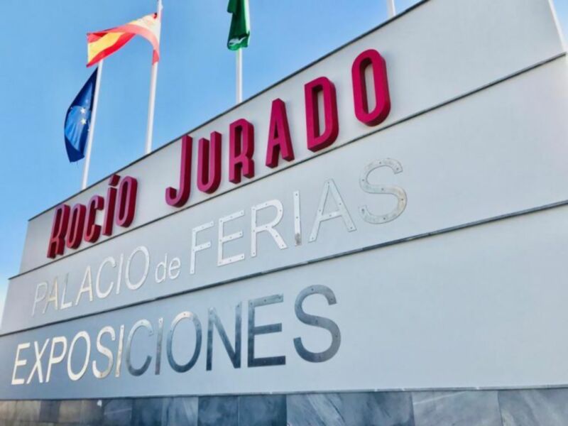 Palacio de Ferias Rocio Jurado con banderas española y portuguesa en el cielo azul claro. Exposición de eventos y actividades culturales en la ciudad de Sevilla, España.