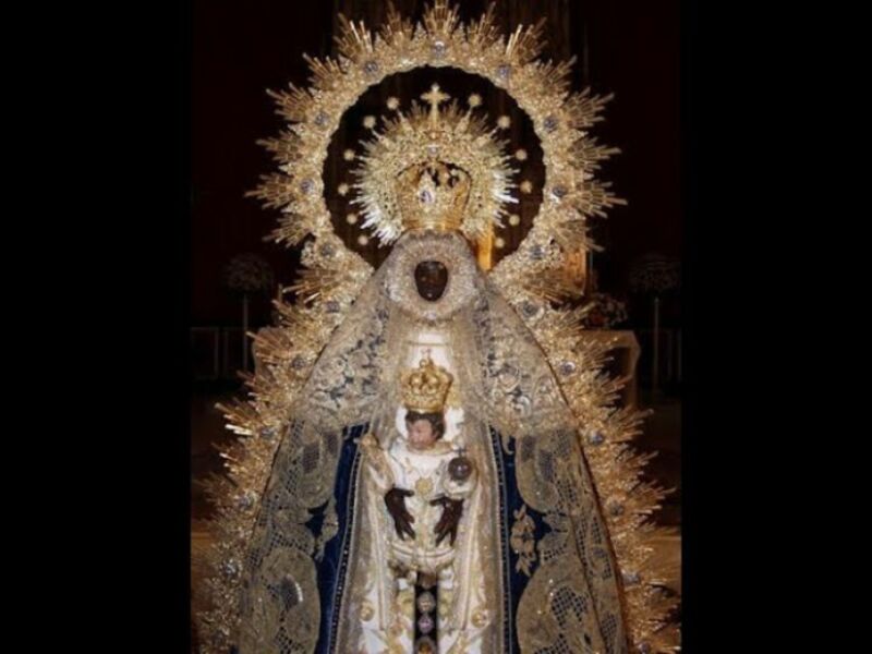 Imagen de la Virgen María con una corona dorada y ornamentos religiosos.