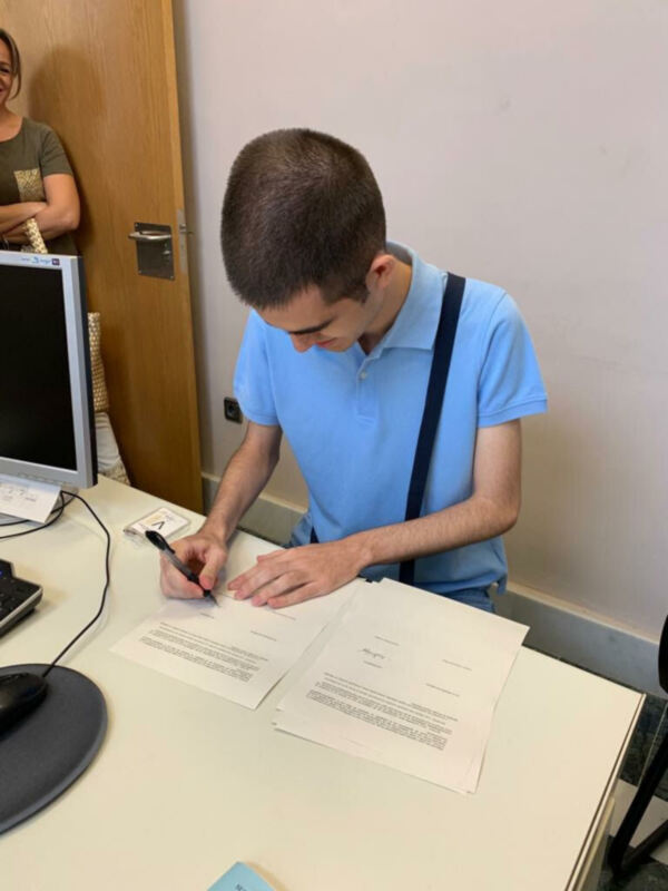 Persona firmando documentos en una oficina.