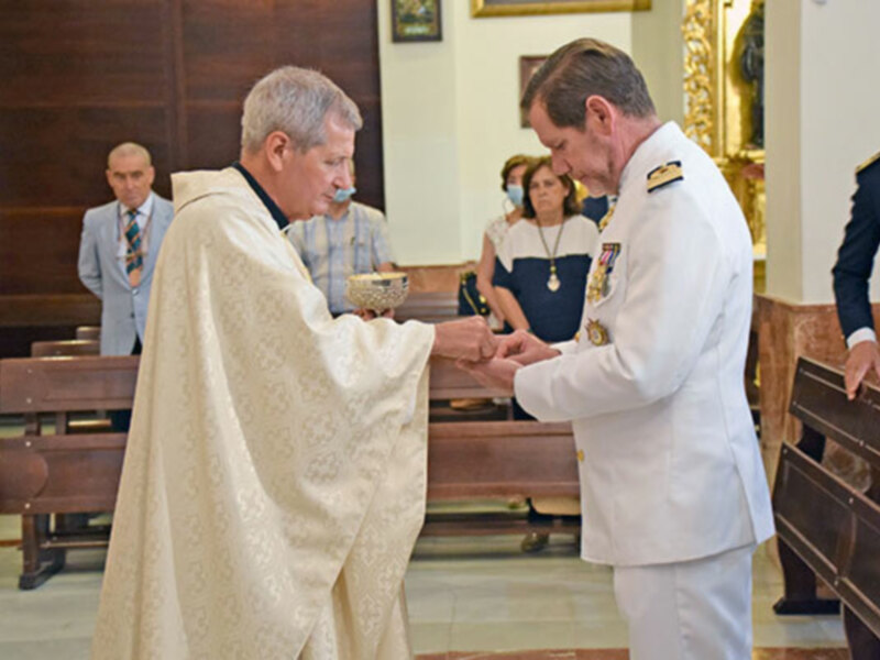 Un clérigo y un oficial militar intercambian una bendición en una ceremonia religiosa en una iglesia.