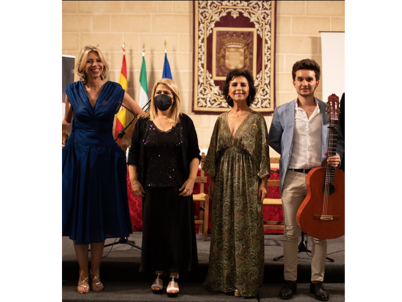 Cuarteto musical en escenario con banderas y decoración clásica.