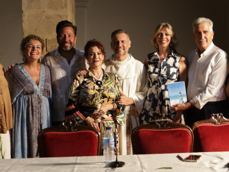 Una celebración en un entorno elegante, con una persona sosteniendo un libro titulado 'Sueños Infinitos'. La escena sugiere una reunión formal o una presentación de libro.