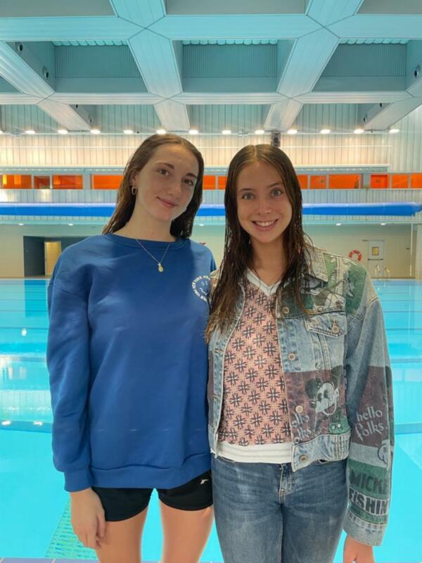 Dos jóvenes posan en la piscina, disfrutando de su tiempo en el agua.