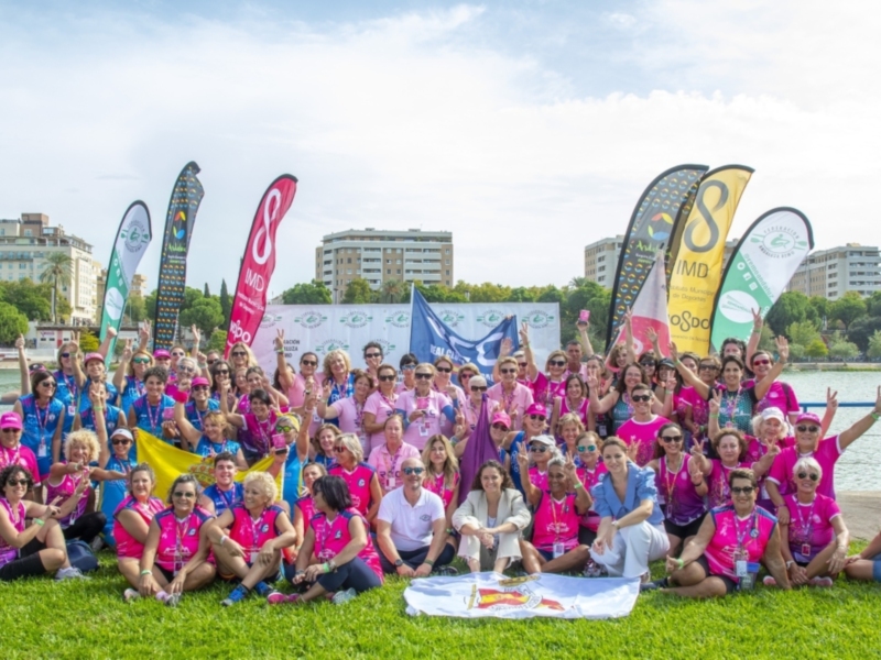 Grande grupo de personas en camisetas rosas celebrando juntos en un parque junto a un lago.