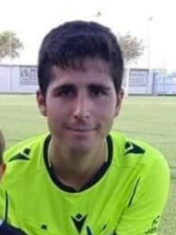Joven futbolista en campo de fútbol, uniforme verde y blanco