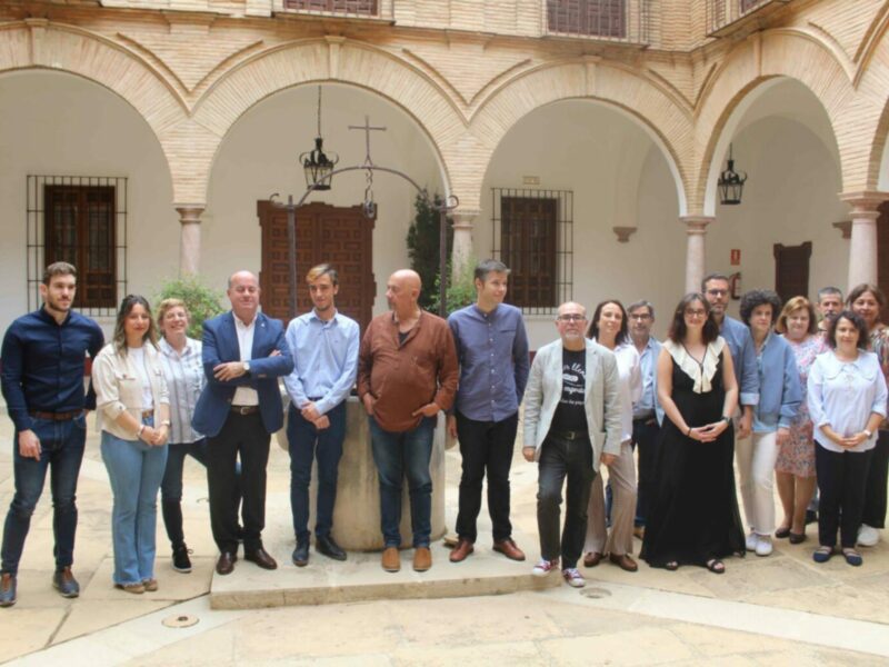 Grupo de personas posando en un patio histórico con arcos y columnas.