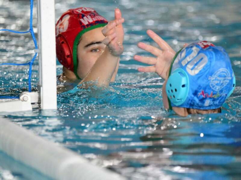 Jugadores de waterpolo en acción durante un partido en piscina.