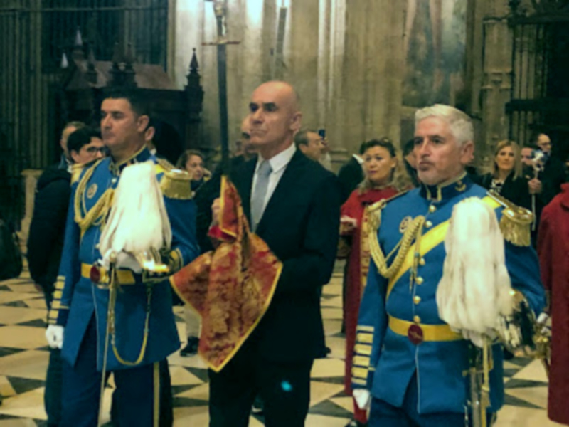Imaginaria escena de una ceremonia oficial en un palacio, con personas vestidas formalmente.