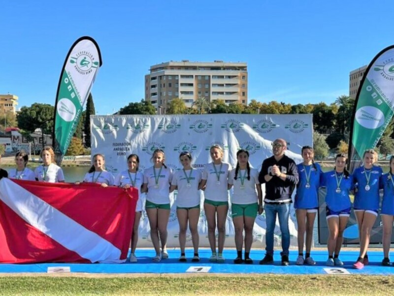 Equipo de nadadores celebrándose en el podio de un evento deportivo, con banderas y logotipos en el fondo.