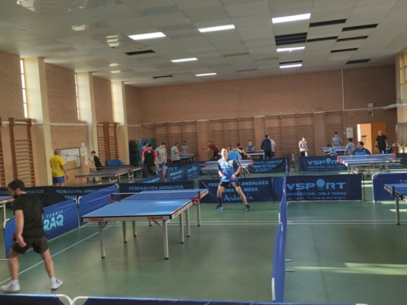 Salón de tenis de mesa con varios jugadores en acción.