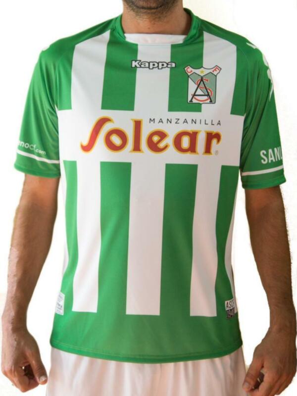 Camiseta de fútbol con rayas verticales verdes y blancas, logotipo 'Kappa' y sponsor 'Solear Manzanilla' en el centro. Diseño clásico de clubes de fútbol.