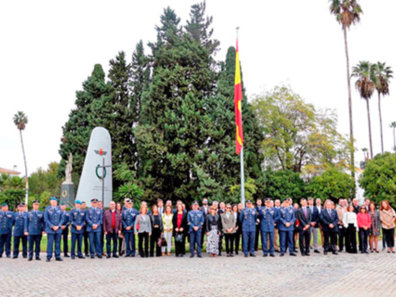 Fotografía de un grupo de personas uniformadas posando frente a un monumento militar, con árboles y banderas en el fondo.