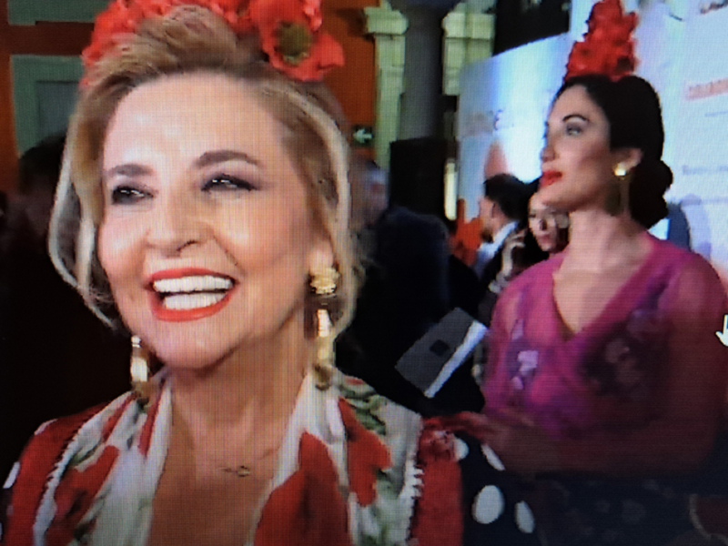 Mujer sonriente con flores en el cabello en un evento formal.