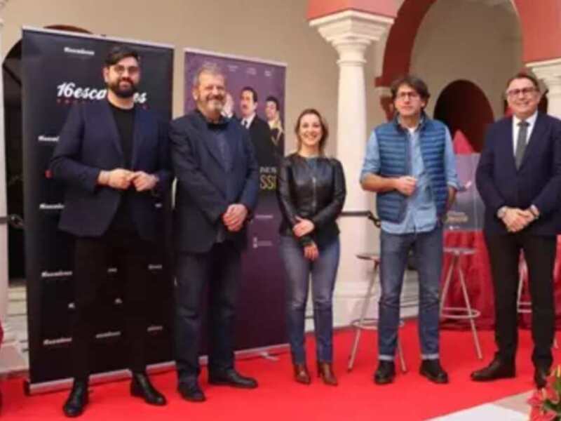 Presentación de '16escos' en un evento formal con paneles de fondo y personal en trajes.
