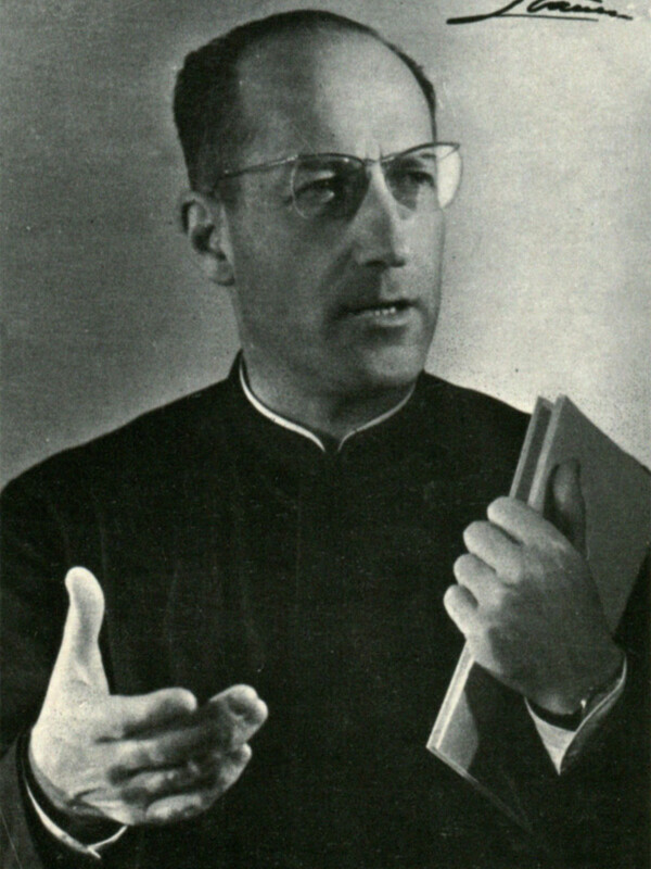 Retrato de hombre hablando y sosteniendo un libro, vestido con traje oscuro y gafas, firmado en la esquina superior derecha.