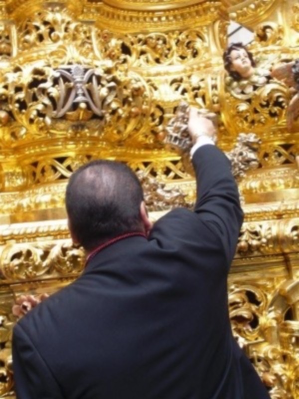 Un hombre trabajando en una estructura dorada con detalles artísticos en un entorno de alta arquitectura.