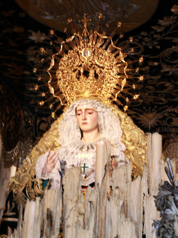 Imagen de la Virgen del Rocío, con una corona dorada y vestimentas blancas, en un contexto religioso y festivo.