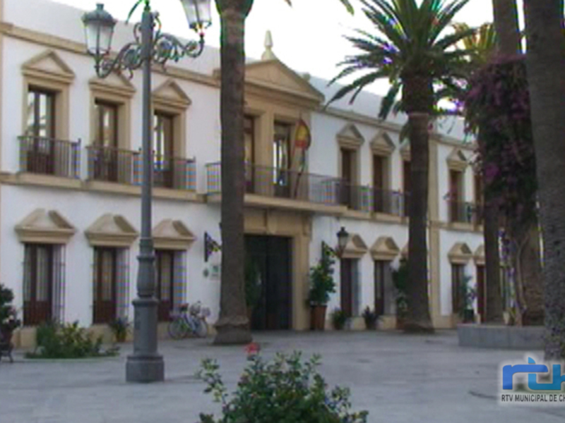 Plaza con edificio colonial y palmeras, típico de Chipiona, España.
