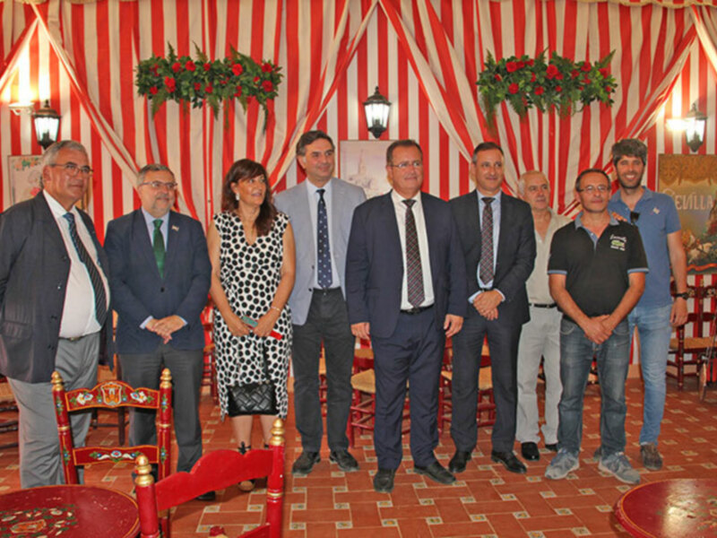 Grup de persones en una sala decorada amb estendards roges i blancs, probablement en una cerimònia o acte oficial.