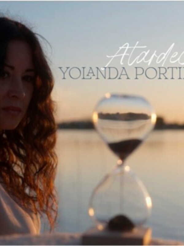 Una mujer con cabello largo y ondulado, mirando hacia el horizonte, con un reloj de arena en el frente. El texto 'Atardecer' y 'Yolanda Portillo' se encuentran en la parte superior de la imagen.
