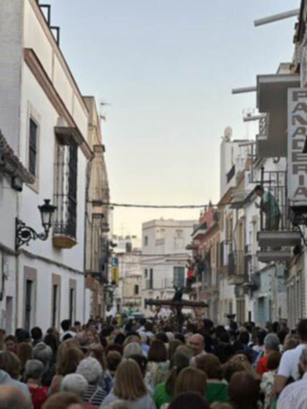 Callejón animado con gente caminando y edificios históricos en el fondo, en un día soleado.