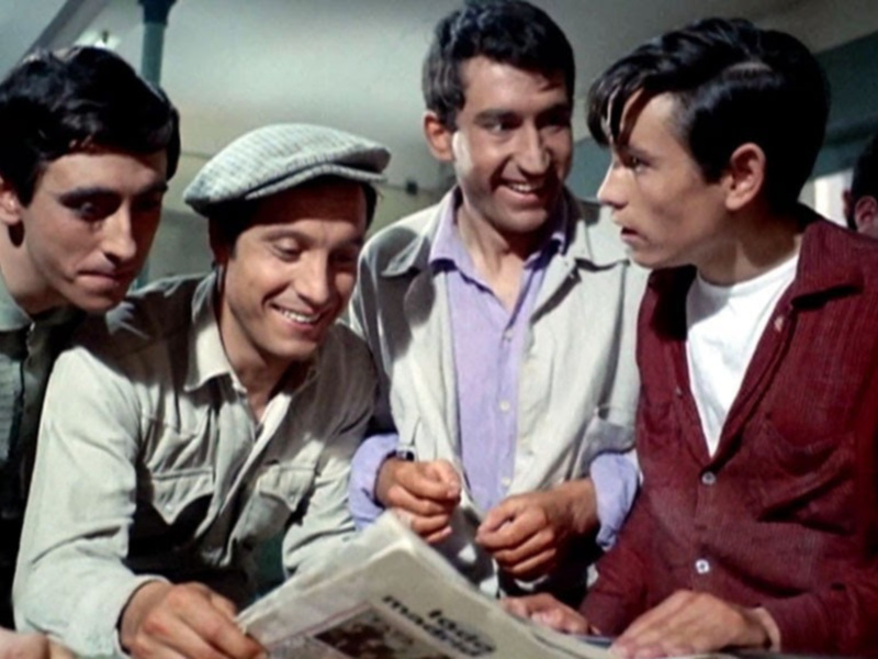 Un grupo de jóvenes se reúne para leer un periódico, compartiendo una sonrisa y un momento de camaradería.