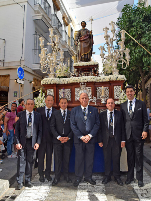 Oficiales y autoridades posan junto a la procesión de San Juan Bautista en una celebración religiosa.