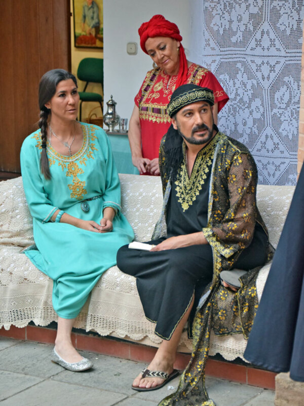 Una pareja vestida con trajes tradicionales, posando en una habitación con muebles y decoración típica.