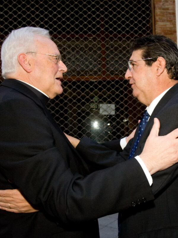 Two men in suits and ties are embracing each other in a friendly gesture.