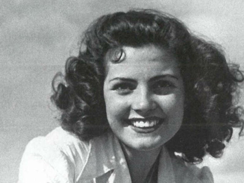 Retrato blanco y negro de una mujer sonriente con cabello rizado, posando de frente.