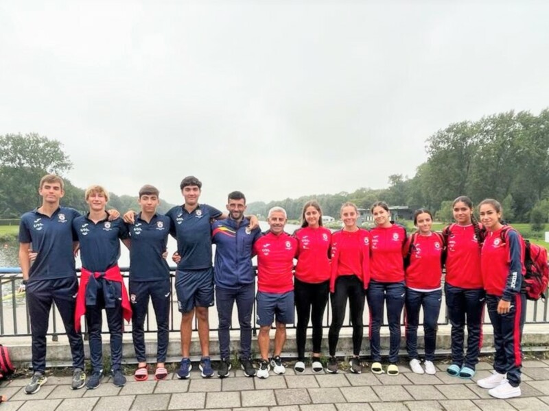 Equipo de remo posando junto al lago en un día nublado.