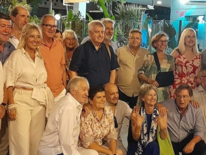 Grupo de personas mayores sonrientes y felices posando juntos en un evento nocturno al aire libre.