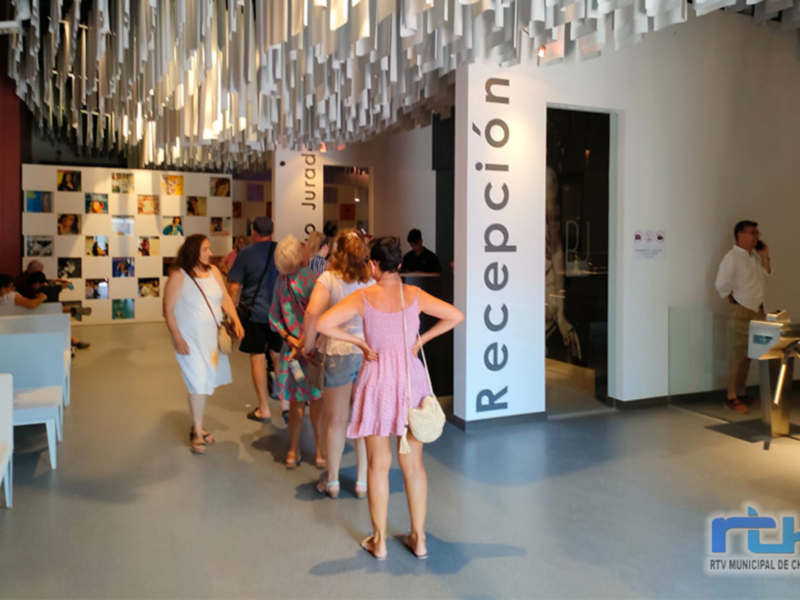 Visitantes explorando una exposición en un museo moderno, con carteles informativos y una recepción visible.