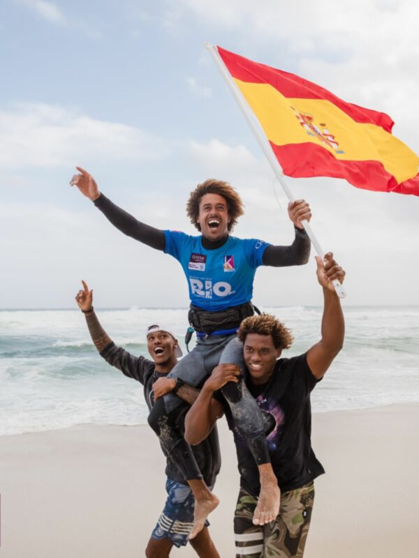 Dos personas celebrándose en la playa, con una bandera española en el aire. La imagen está firmada por Qatar Airways y el GKA Kite World Tour.
