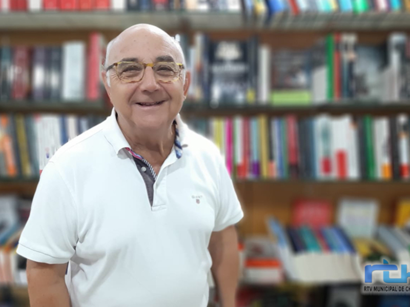 Eduardo Sánchez, un destacado escritor y periodista, posa frente a una biblioteca repleta de libros. Su sonrisa radiante refleja su entusiasmo por la literatura y la educación.