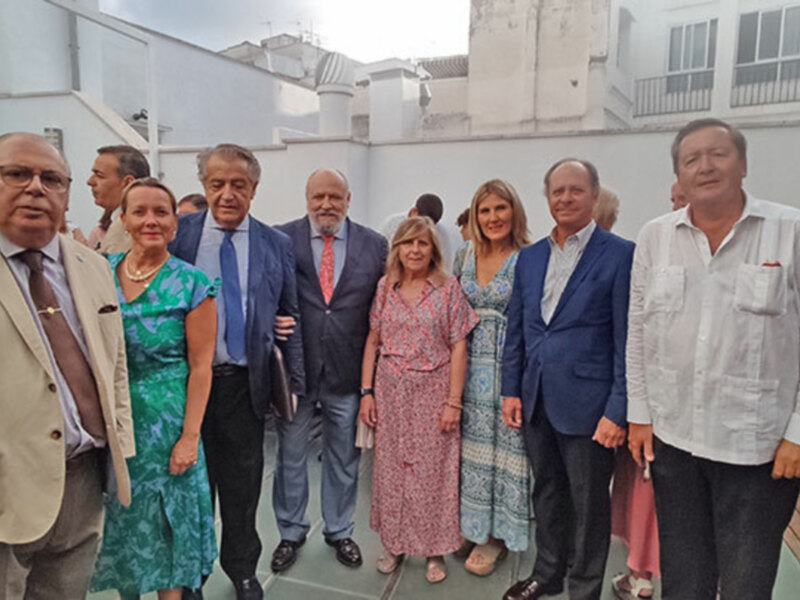 Grupo de personas posando juntos en una terraza con vistas urbanas al fondo.