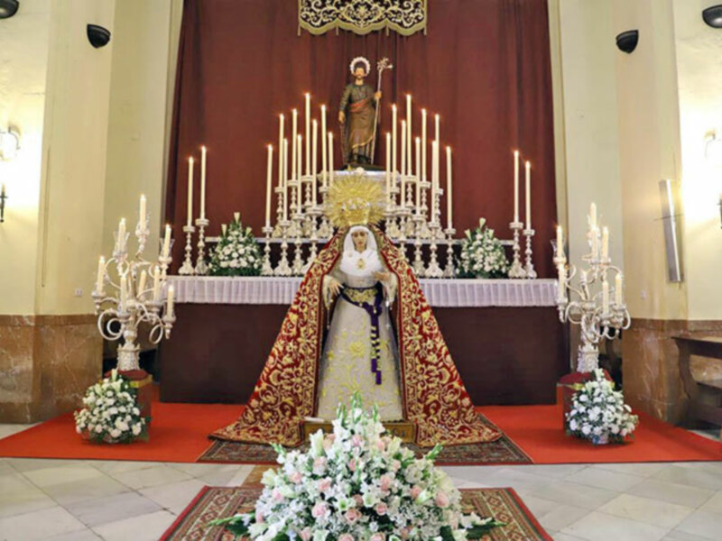 Altar con estatua de la Virgen María y candelabros, decorado con flores y velas en una iglesia.