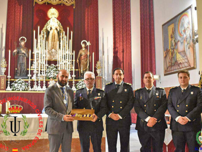 Personalidades militares y civiles posando para una foto en un ambiente ceremonial con una estatua religiosa en el fondo.