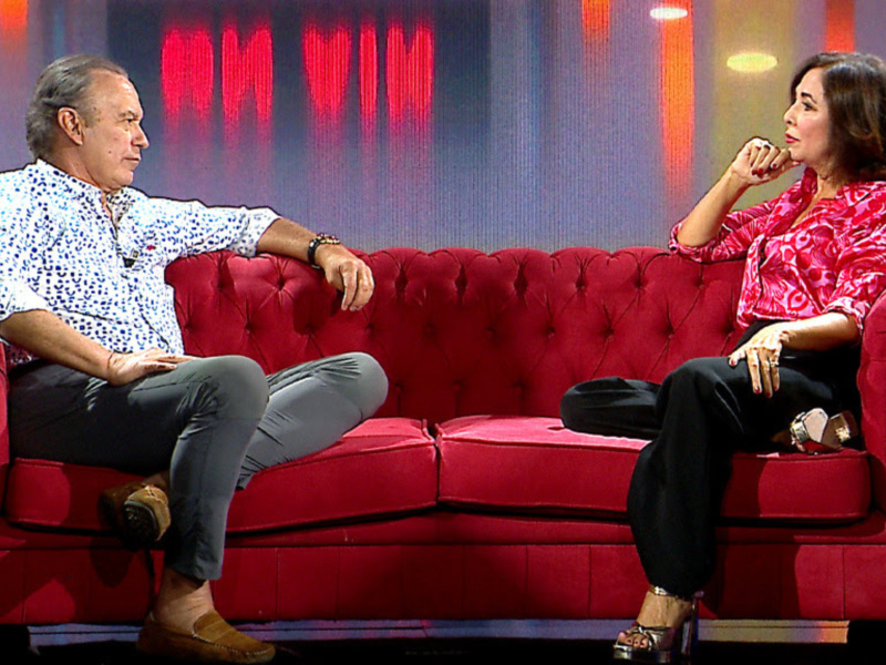 Entrevista en sofá rojo con fondo de luces rojas