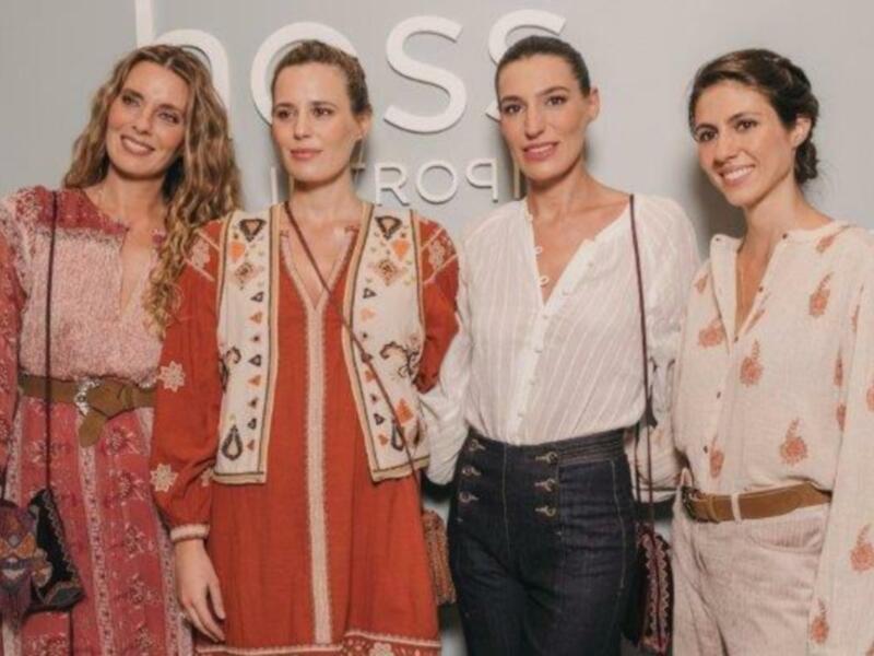 Tres mujeres posando frente a un fondo con el logo de Hugo Boss en una celebración o evento empresarial.