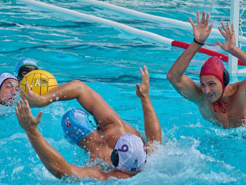 Jugadores de waterpolo en acción durante un partido, luchando por el balón en el agua.