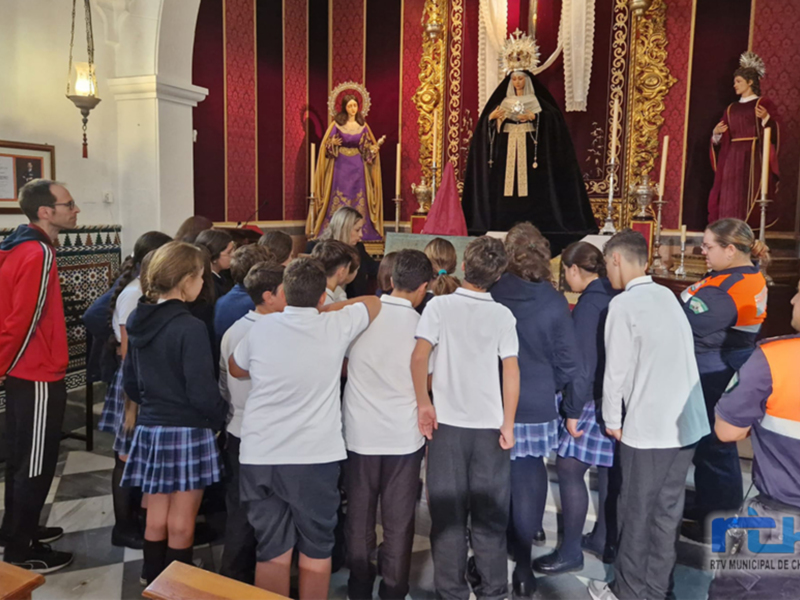 Visita escolar a la iglesia, niños y adultos en oración frente a la imagen de la Virgen del Carmen.