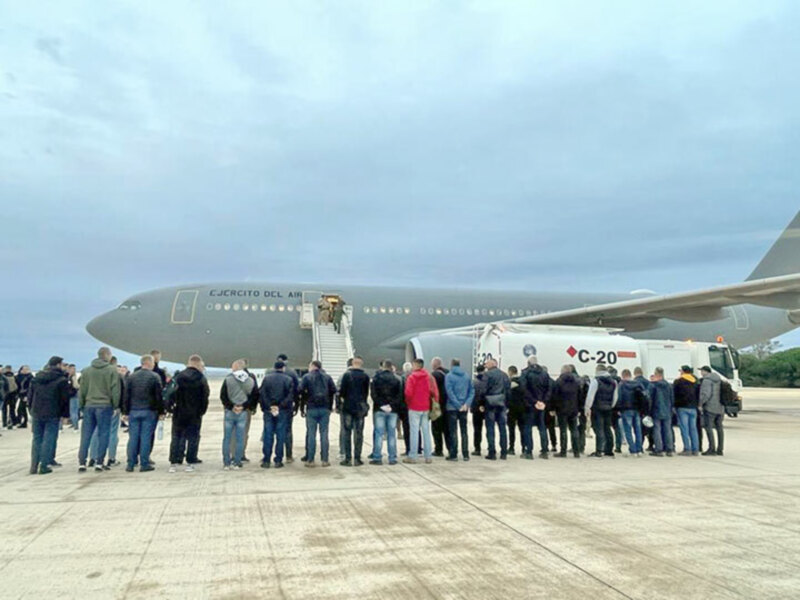 Gente esperando en el suelo junto a un avión militar C-20 de Ejército del Aire. El cielo está nublado.