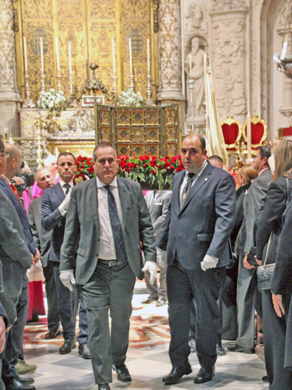 Procesión en una catedral con participantes en trajes formales, en un ambiente solemne.