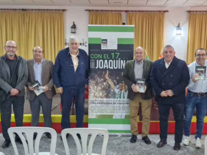 Una reunión formal en un salón con una bandera y un cartel informativo, donde se presentan los detalles de un evento o una presentación.