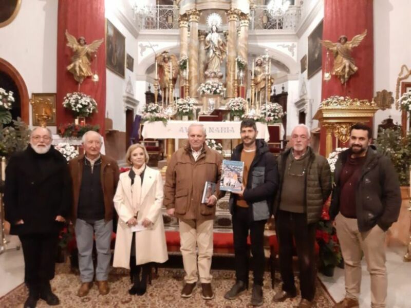 Grupo de personas posando en el interior de una iglesia decorada con flores y estatuas religiosas.