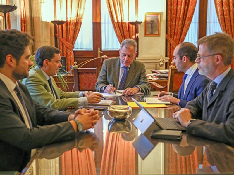 Reunión de negocios en un ambiente formal con documentos y tecnología digital en uso.