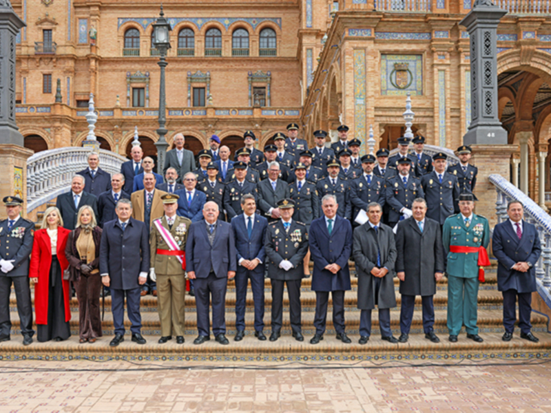 Grupo de personas en uniforme posando para una foto en una escalera con un edificio histórico en el fondo.